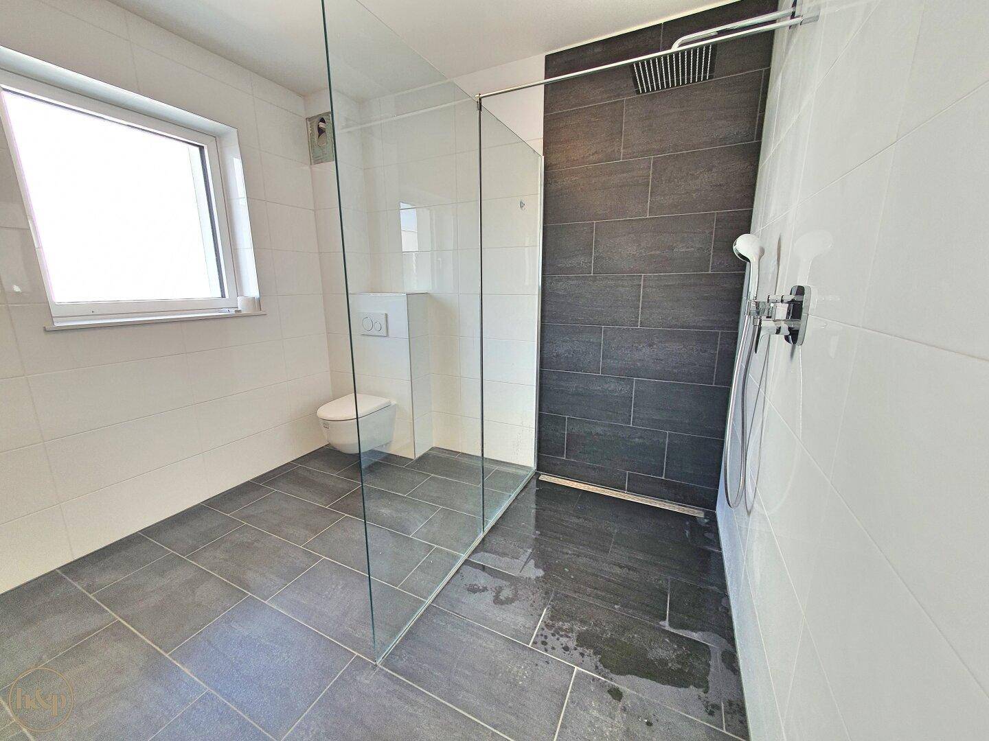 Geräumiges Badezimmer mit moderner begehbarer Dusche und großformatigen Fliesen.
