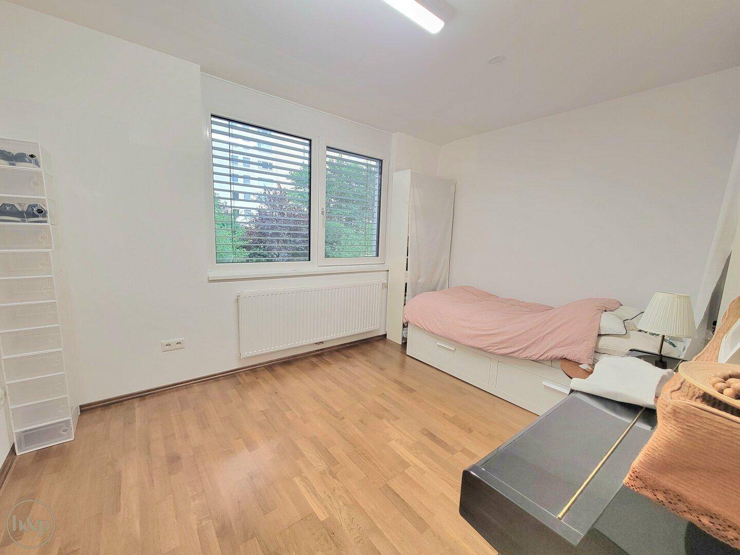 Helles Schlafzimmer mit Holzboden und großen Fenstern, bietet viel Tageslicht und eine angenehme Atmosphäre.