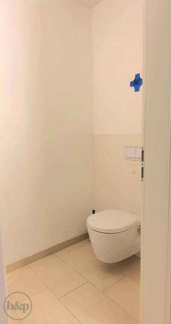 Separates Gäste-WC mit wandhängender Toilette und hellen Fliesen, minimalistisch und sauber.