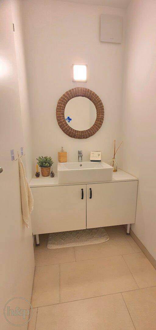 Modernes Gäste-WC mit stilvollem Waschbecken, Spiegel und hellen Fliesen, einladend und gepflegt.