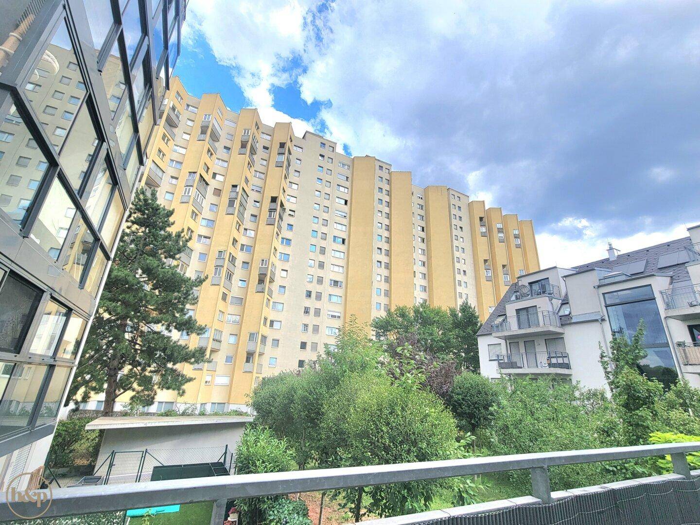 Blick auf moderne Wohngebäude mit vielen Fenstern und Balkonen, umgeben von Grünflächen.