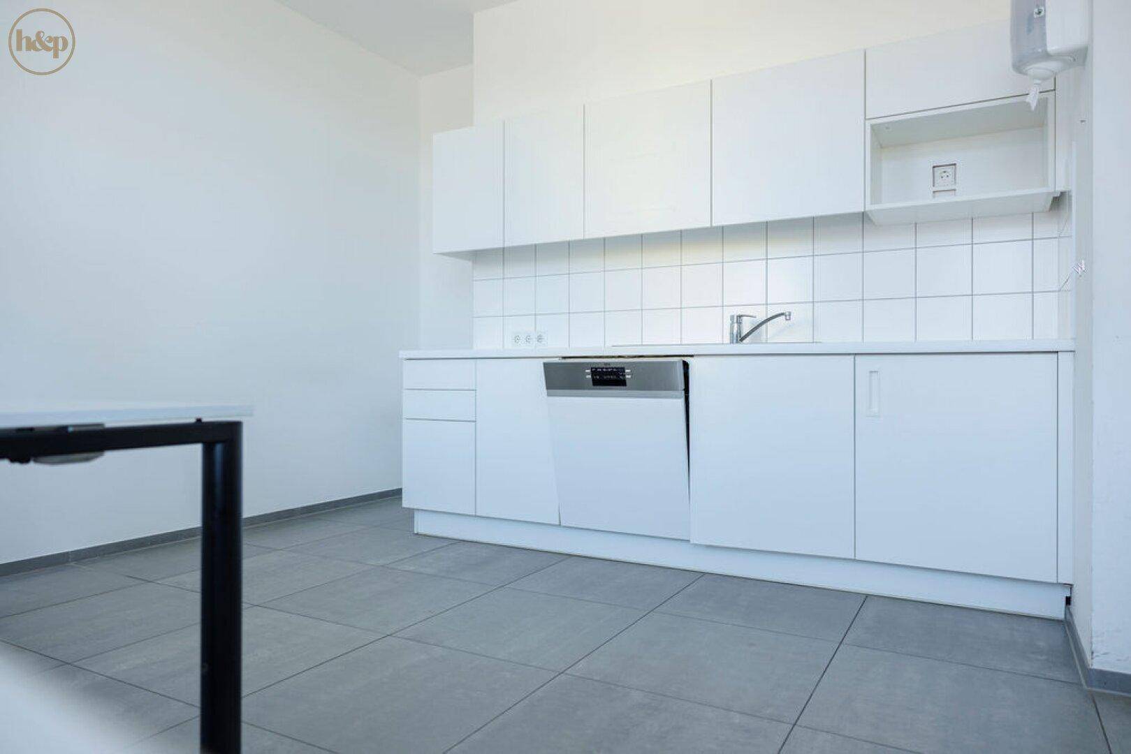 Schlichte weiße Küchenzeile mit Spülmaschine, Spüle und Fliesenrückwand in einem Büro.
