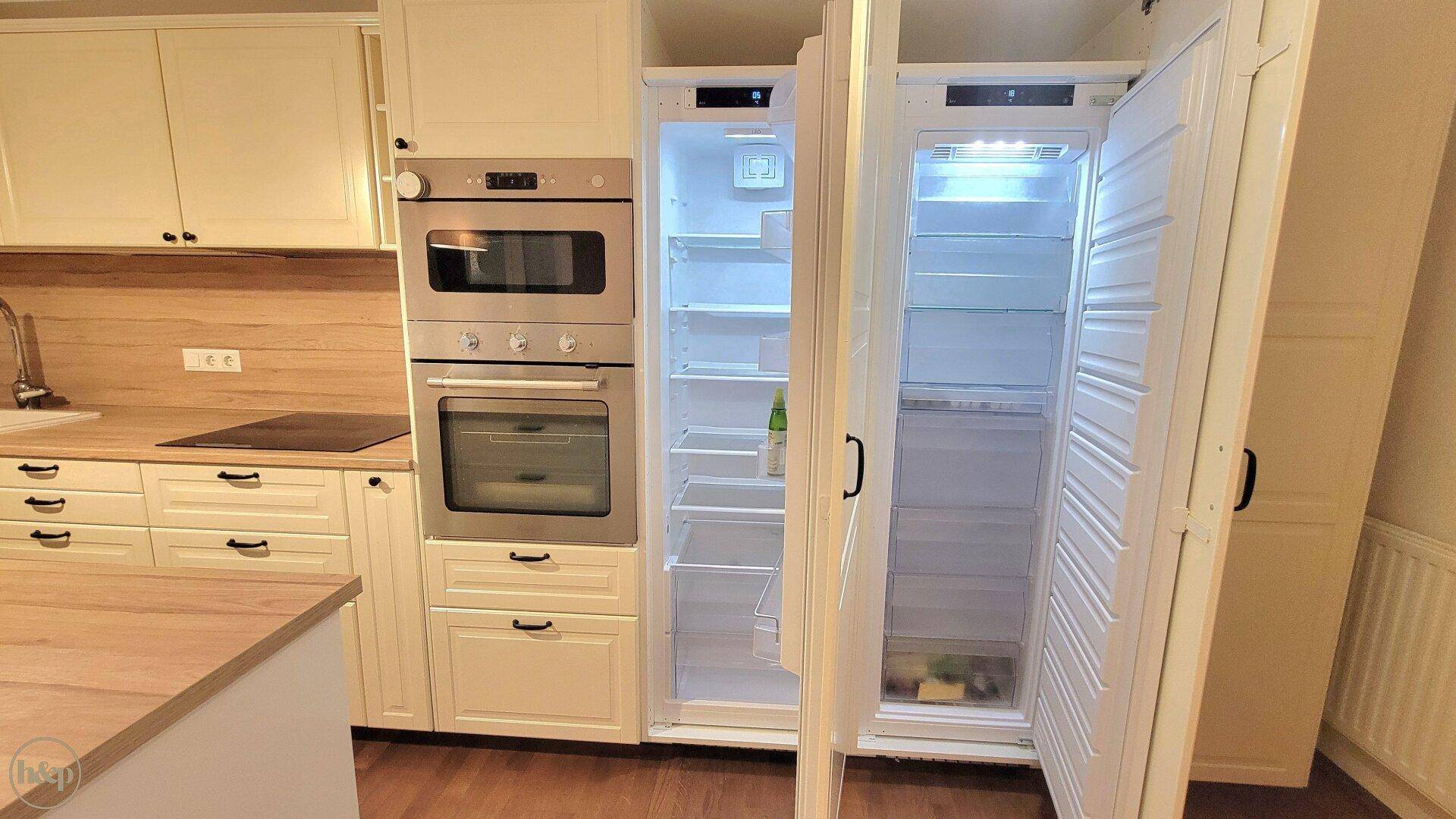 Detailansicht der modernen Einbauküche mit integriertem Backofen, Mikrowelle und Kühlschrank.