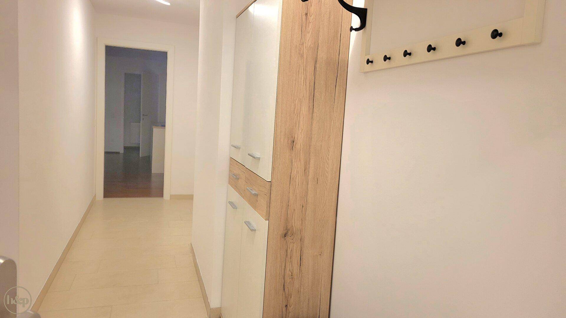 Heller Flur mit modernem Schrank, Garderobe und Zugang zu weiteren Räumen.