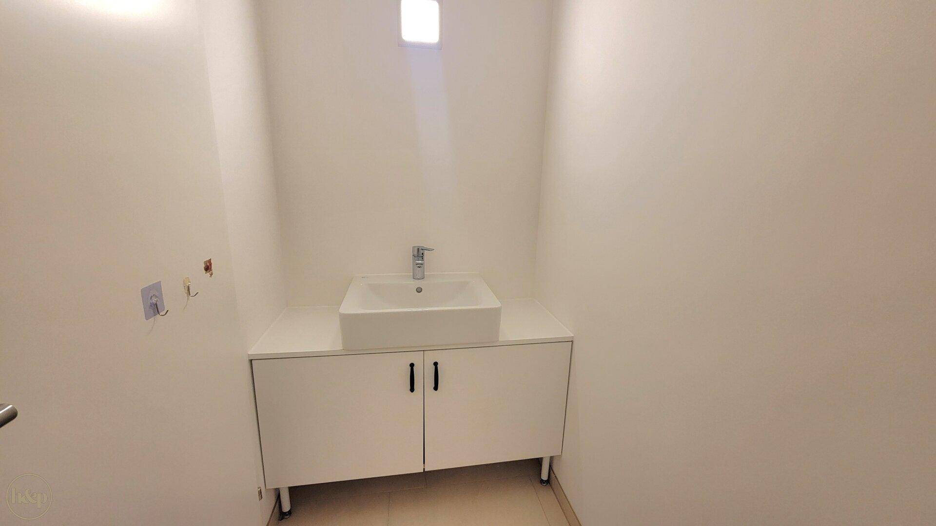 Kleiner Raum mit modernem Waschbecken auf einem weißen Unterschrank.