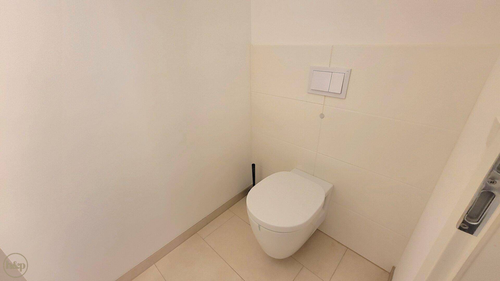 Modernes Wand-WC in einem hell gefliesten Raum mit minimalistischem Design.