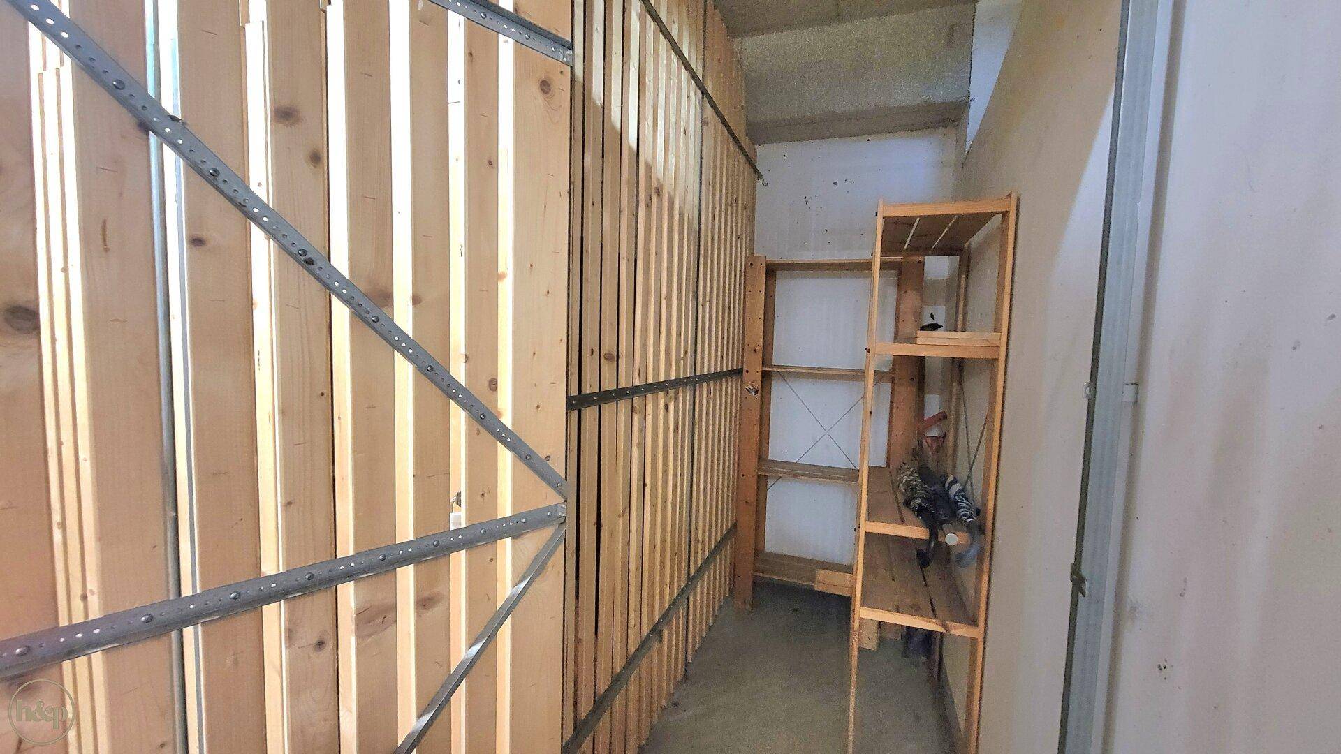 Geräumiger Kellerabteil mit Holzabtrennungen und Regalen für zusätzlichen Stauraum.
