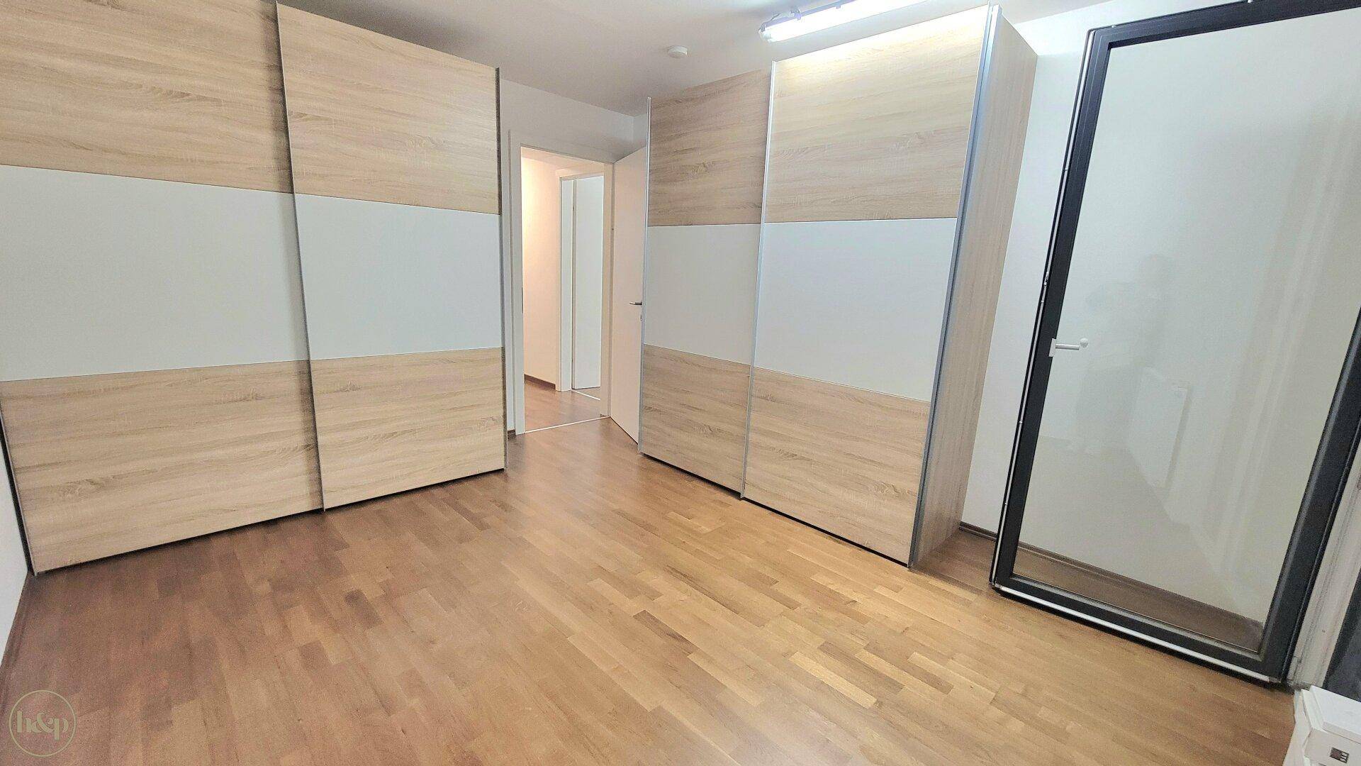 Schlafzimmer mit zwei großen Schiebetürenschränken und hellem Holzboden.