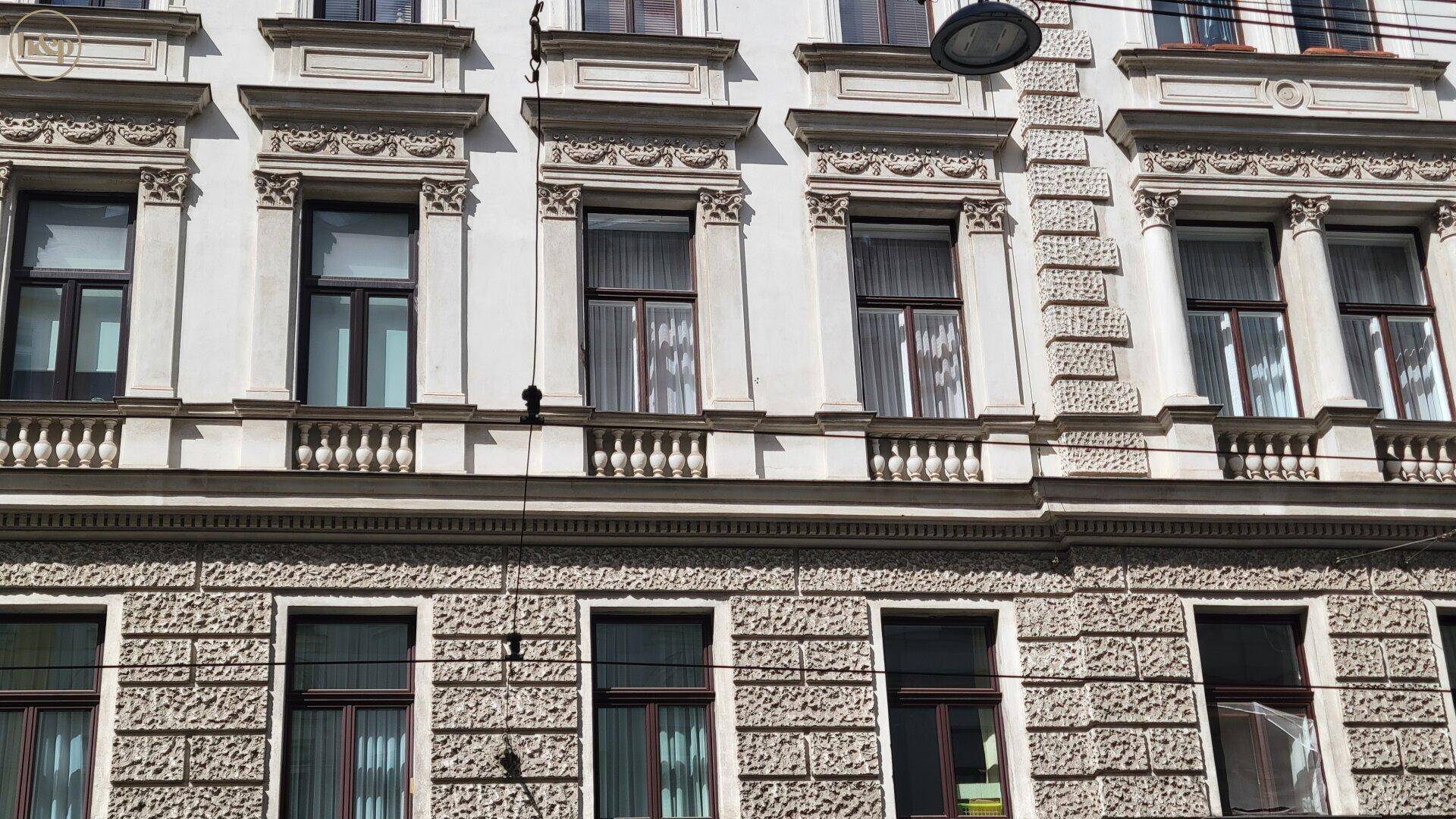 Detailansicht der verzierten Fassade eines Altbaus mit Balkonen und Fenstern.