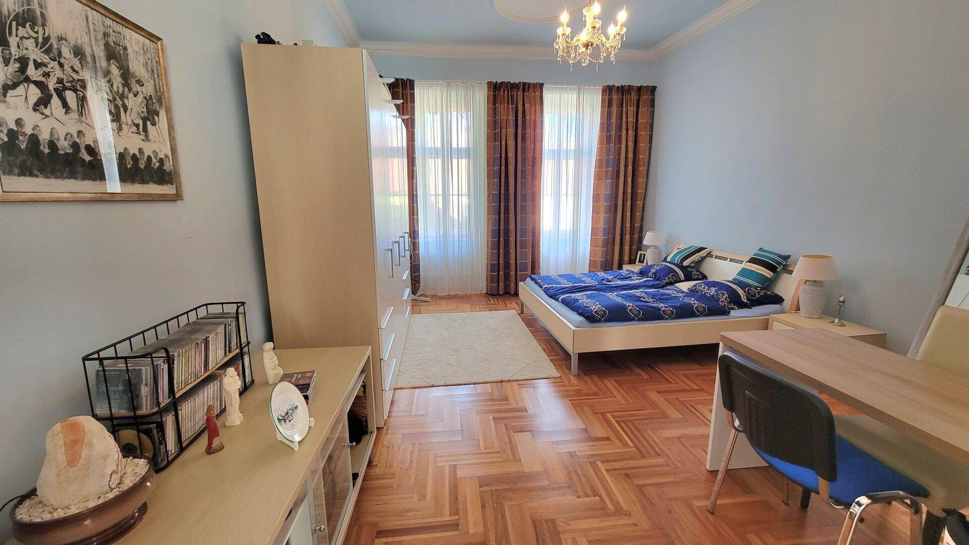 Helles Schlafzimmer mit Parkettboden, Doppelbett und großem Kleiderschrank.