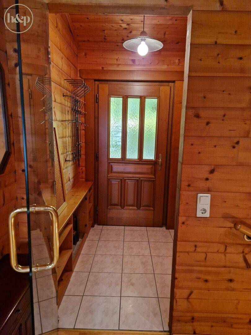 Eingangsbereich mit Holztür, Fliesenboden und Garderobe in rustikalem Stil.