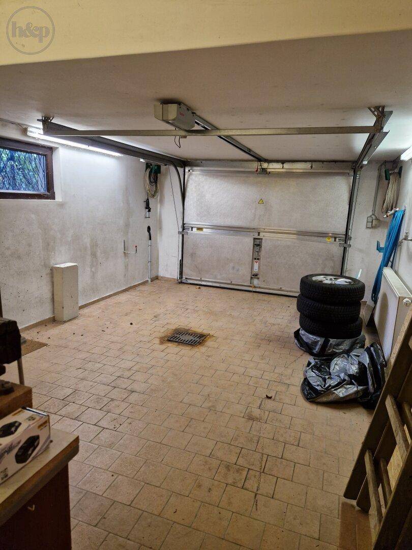 Geräumige Garage mit Fliesenboden, Fenster und Stauraum.