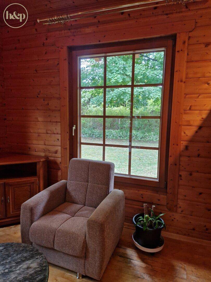 Bequemer Sessel am Fenster mit Blick auf die grüne Umgebung und Holzwände.
