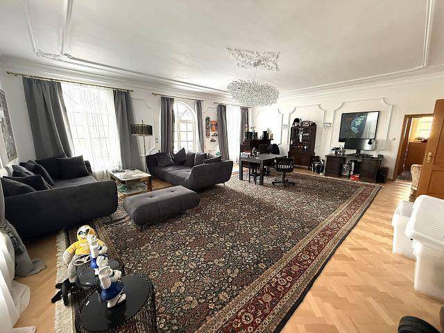Großes Wohnzimmer mit Parkettboden, Stuckdecke und modernen Sofas.