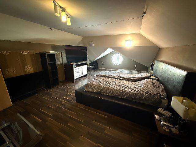 Dachgeschoss-Schlafzimmer mit schrägen Wänden, Holzboden und Dachfenster.