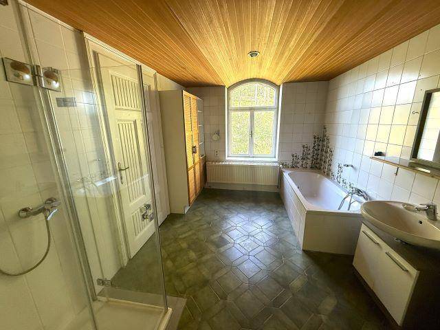 Geräumiges Badezimmer mit Badewanne, Dusche und Holzdecke, ausgestattet mit einem Fenster für Tageslicht.