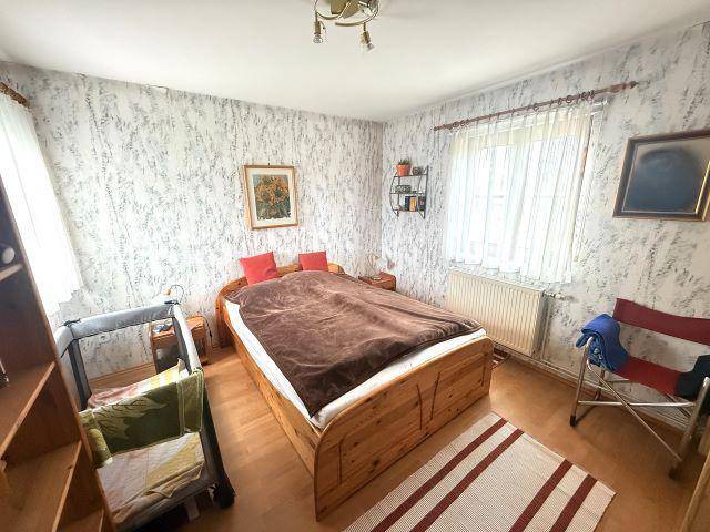 Schlafzimmer mit Doppelbett, gemusterter Tapete und Laminatboden.