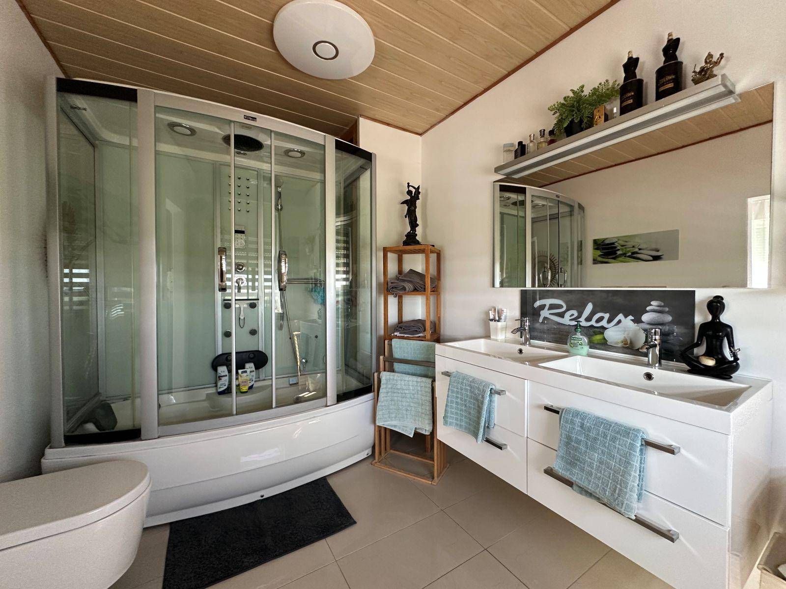 Modernes Badezimmer mit großer Duschkabine, Doppelwaschbecken und Holzdecke.