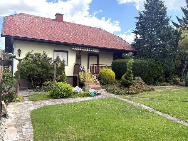 Rückansicht des Hauses mit gepflegtem Garten, Rasenfläche und üppiger Bepflanzung.