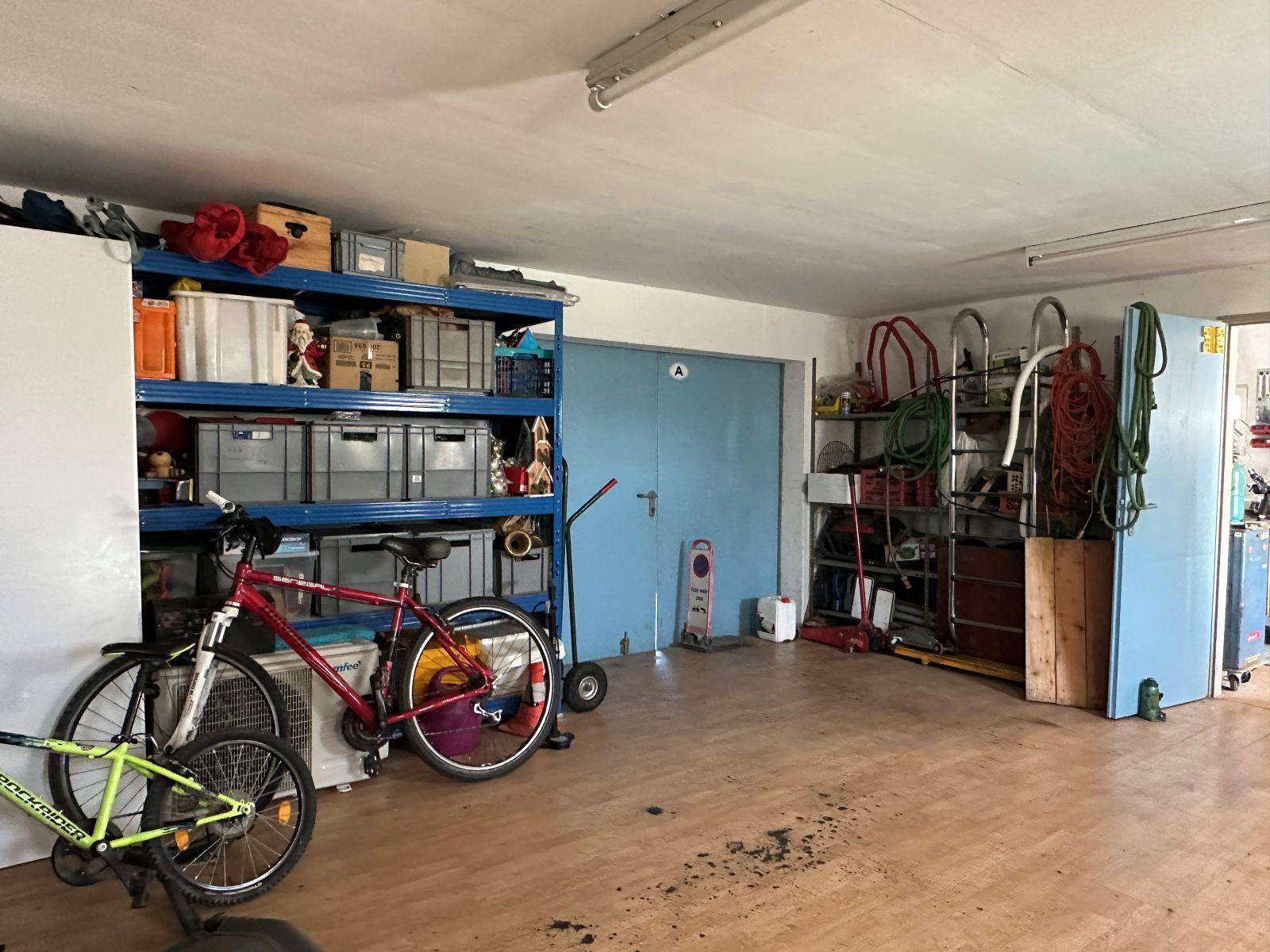 Geräumige Garage mit Regalen, Fahrrädern und viel Stauraum für diverse Gegenstände.