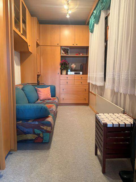 Gemütliches Zimmer mit Sofa, Einbauschränken und Teppichboden, ideal als Gäste- oder Arbeitszimmer.