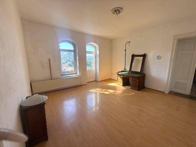 Helles Zimmer mit Holzboden und zwei Fenstern, die einen schönen Ausblick in die Ferne ermöglichen.