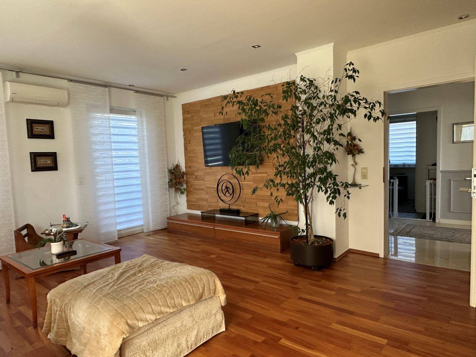 Gemütliches Wohnzimmer mit Holzboden, Akzentwand aus Holz und großem Fernseher.