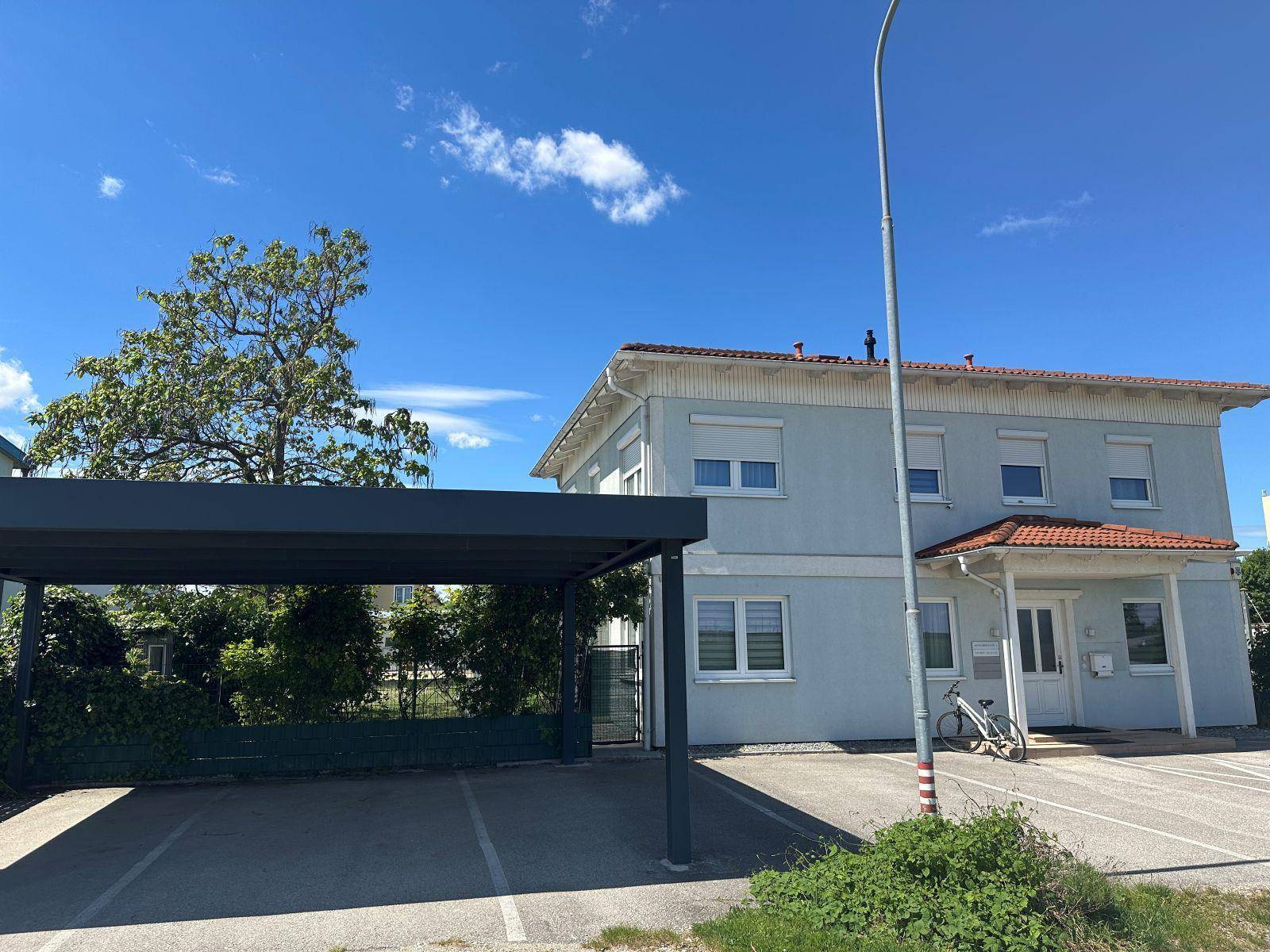 Hausfassade mit modernem Carport und ausreichend Parkmöglichkeiten im Freien.