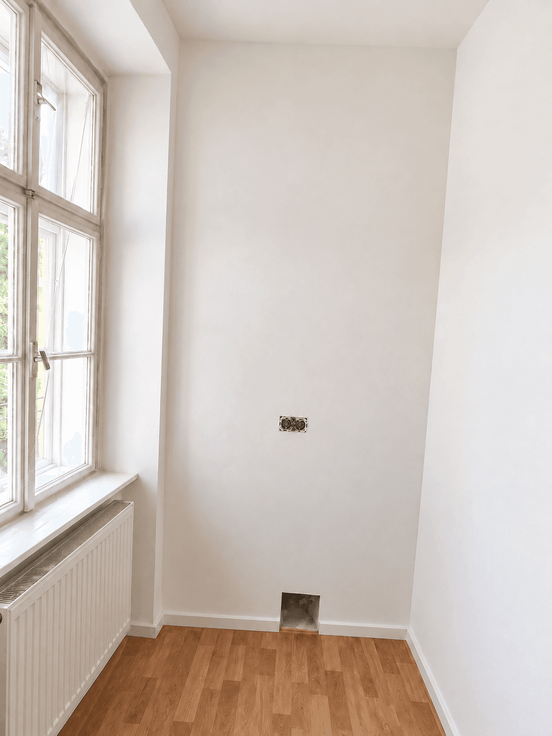Kleiner Raum mit Laminatboden und einem Fenster, vorbereitet für Installationen und Abluft.