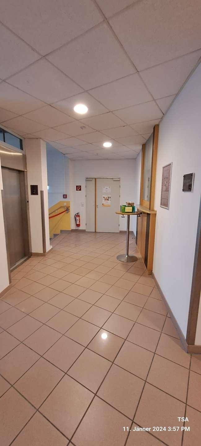 Geräumiger Flur mit Fliesenboden, Aufzug und Zugang zu verschiedenen Räumen.
