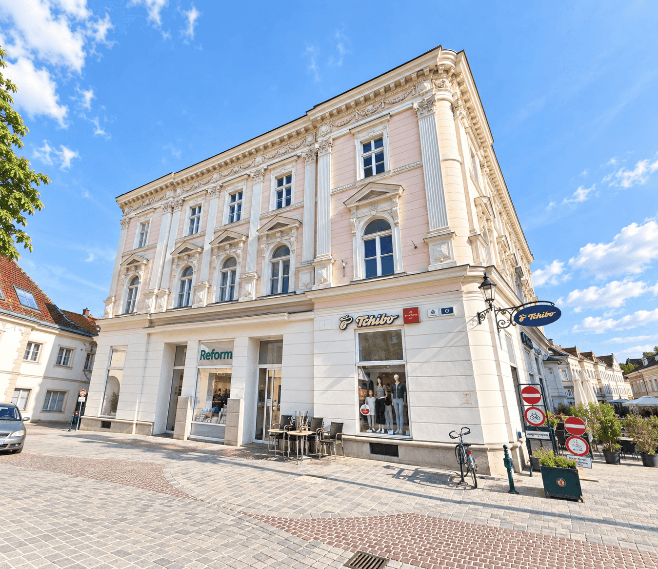 Historisches Gebäude mit Geschäften im Erdgeschoss an einem sonnigen Tag in der Stadt.