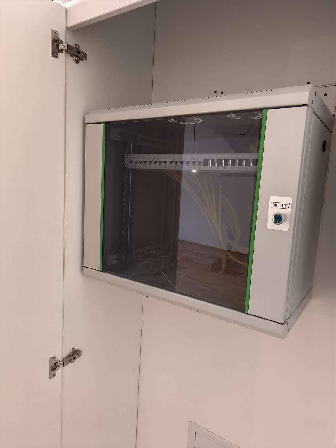 Netzwerkschrank mit Verkabelung in einem weißen Einbauschrank, ordentlich installiert.