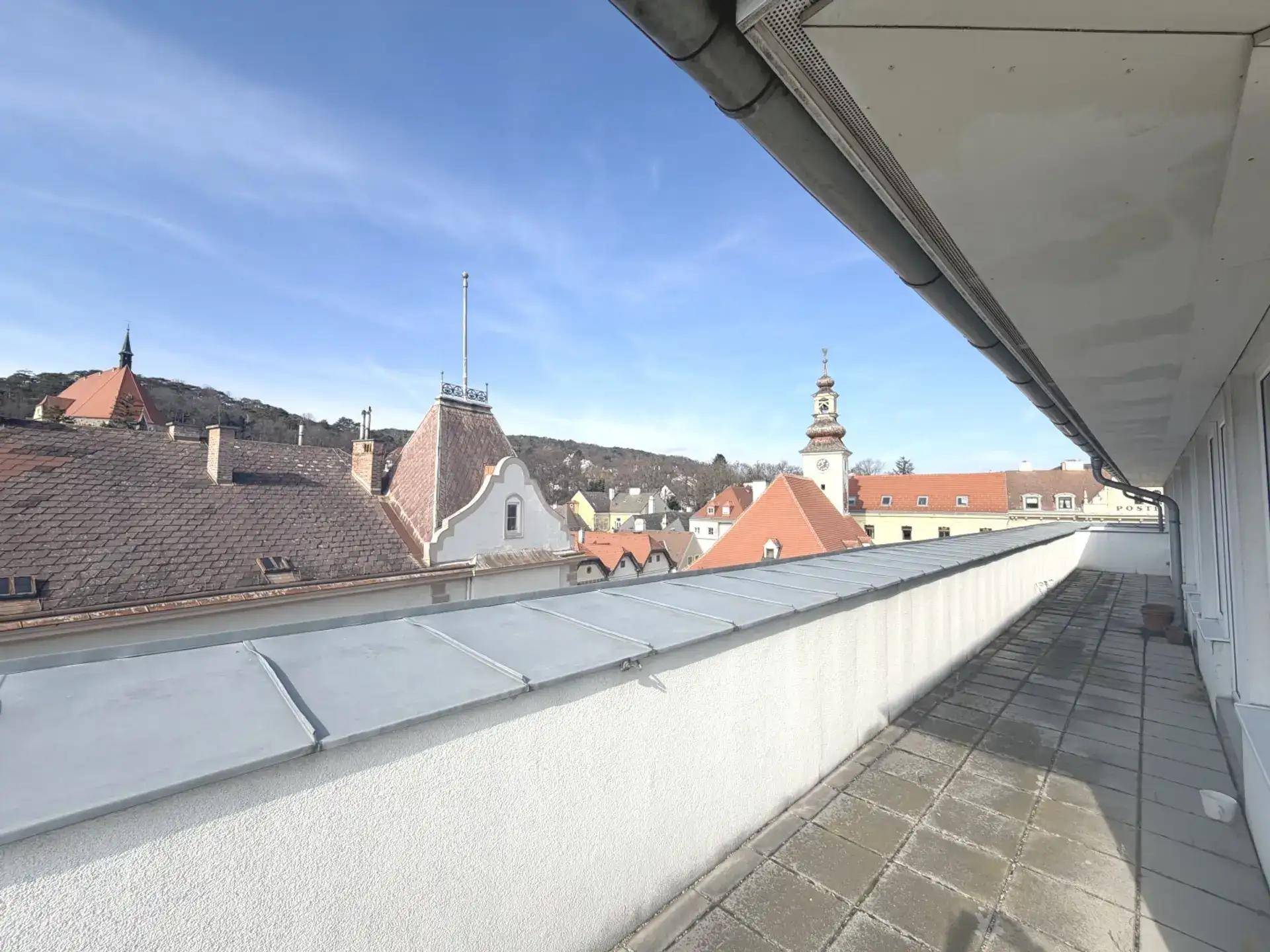 Geräumige Außenterrasse mit Fliesenboden und Panoramablick über die Dächer der Stadt.