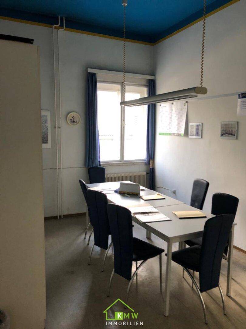 Besprechungsraum mit blau gestrichener Decke, großem Tisch und Stühlen für Zusammenkünfte.