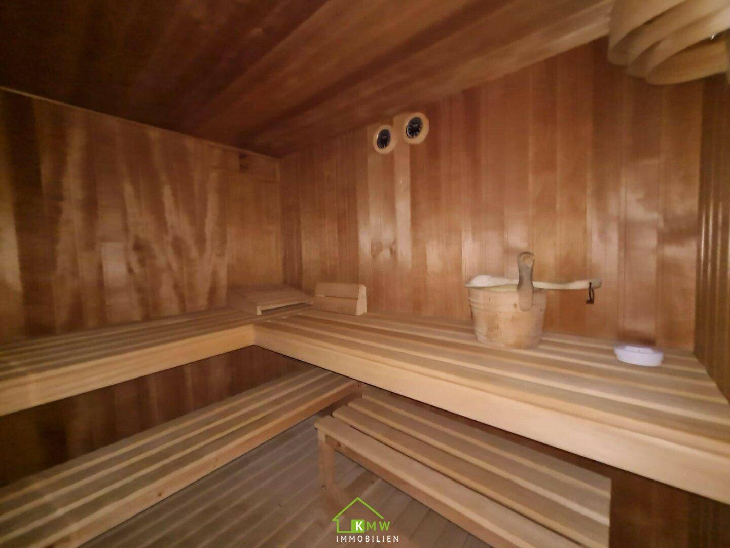 Holzverkleidete Sauna mit mehreren Bänken und traditionellem Zubehör für entspannende Momente.