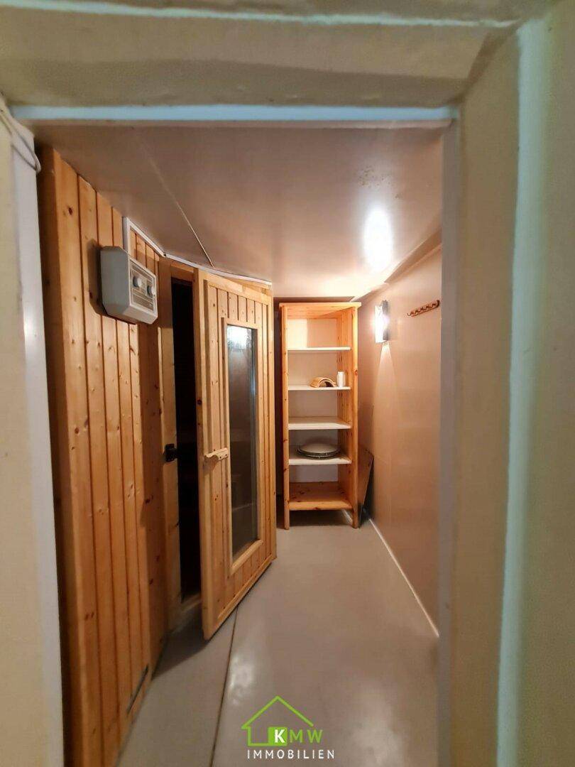 Eingangsbereich zum Saunabereich mit Holzverkleidung und Regal, das eine Wellness-Oase andeutet.