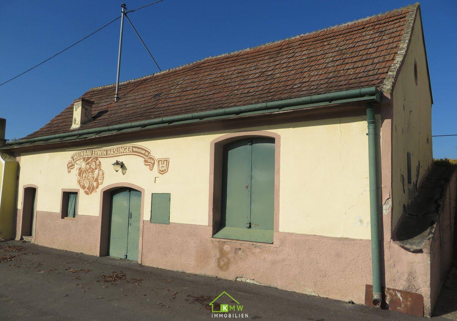 Seitenansicht des historischen Gebäudes mit Ziegeldach und grünen Fensterläden.