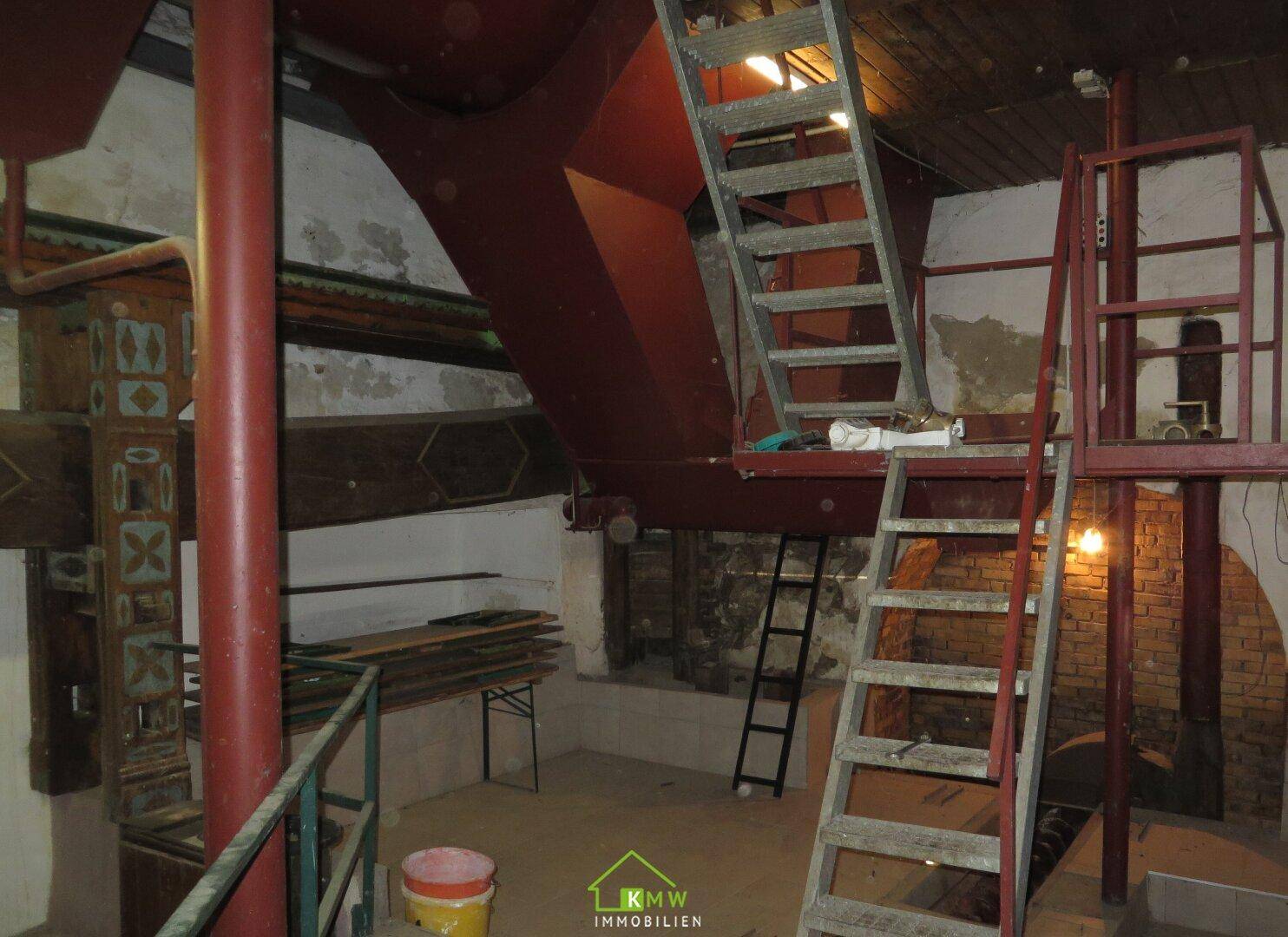 Großer Kellerbereich mit mehreren Ebenen, Metalltreppen und historischen Elementen.