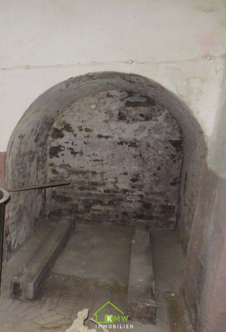 Gewölbte Nische in einem Kellerraum, möglicherweise für Lagerzwecke.