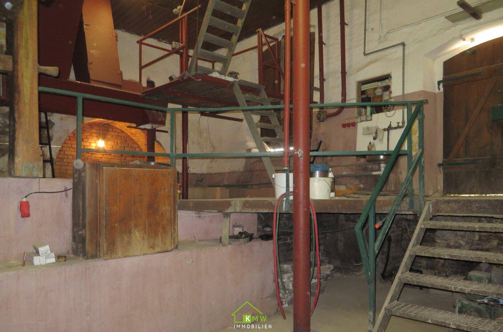 Geräumiger Kellerraum mit Metalltreppen, Geländern und industrieller Ausstattung.