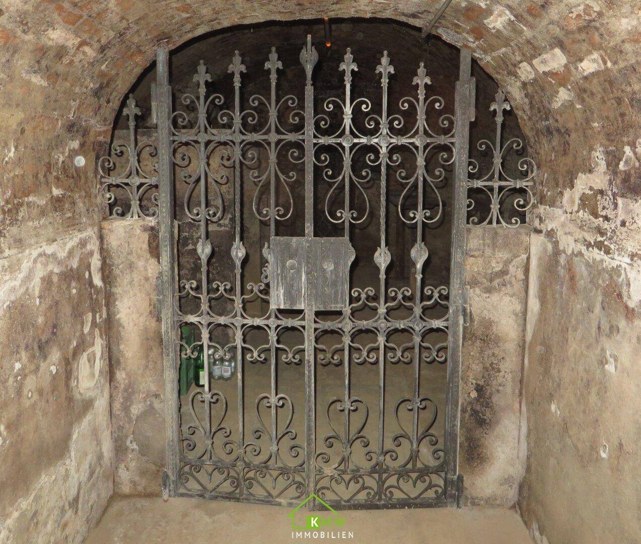 Detailansicht eines schmiedeeisernen Tors in einem historischen Keller.