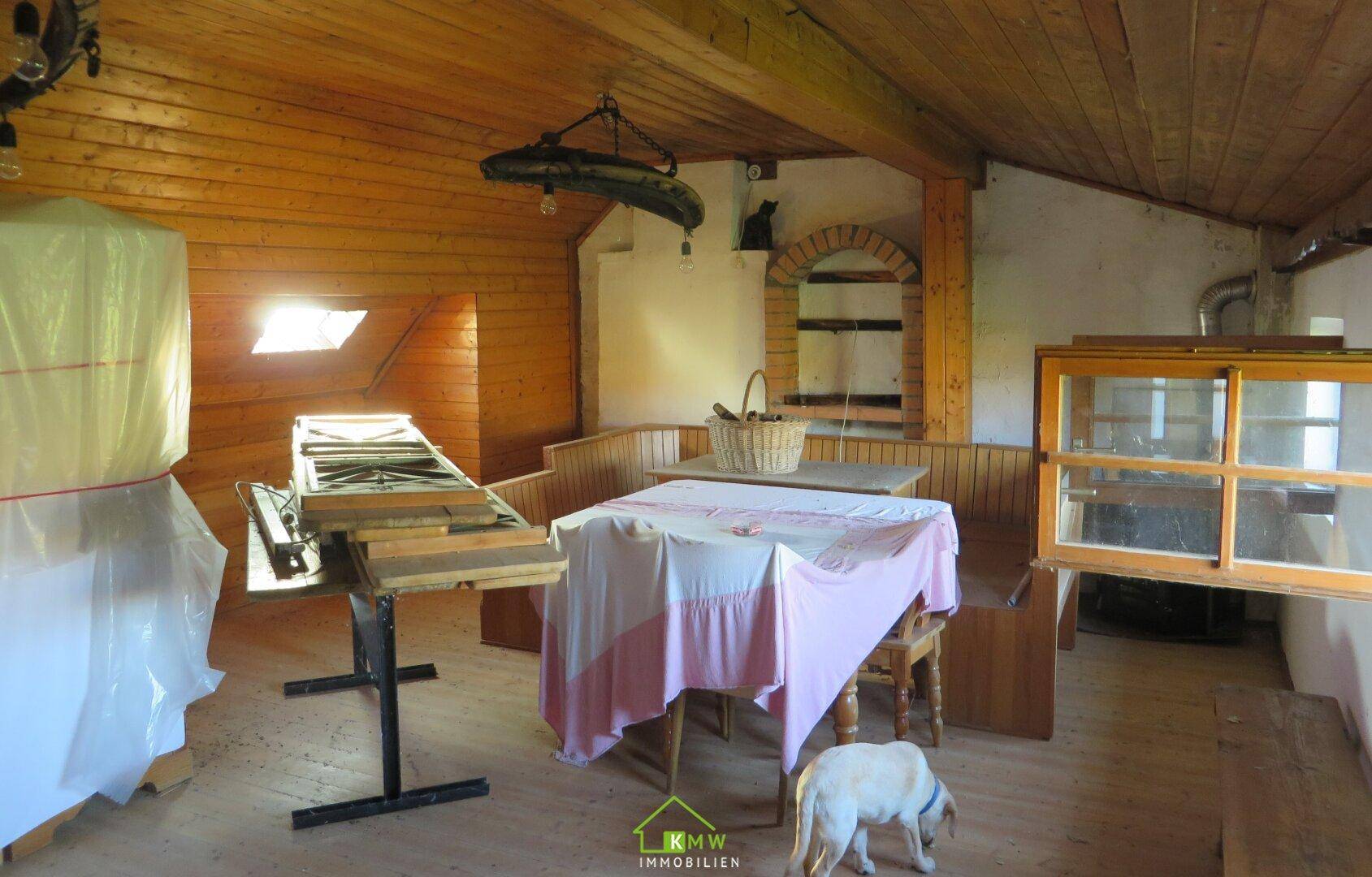 Dachgeschossraum mit Holzbalkendecke, Dachfenstern und rustikaler Einrichtung.