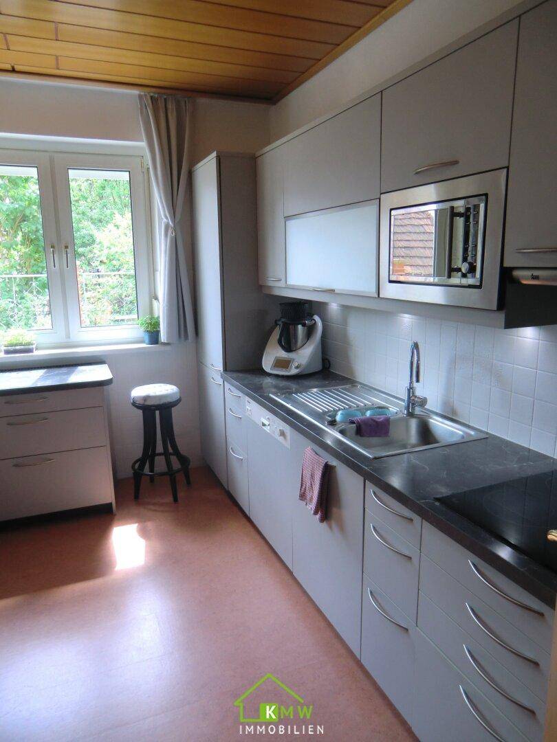 Moderne Küche mit integrierten Geräten, Spüle und Blick durch das Fenster ins Freie.