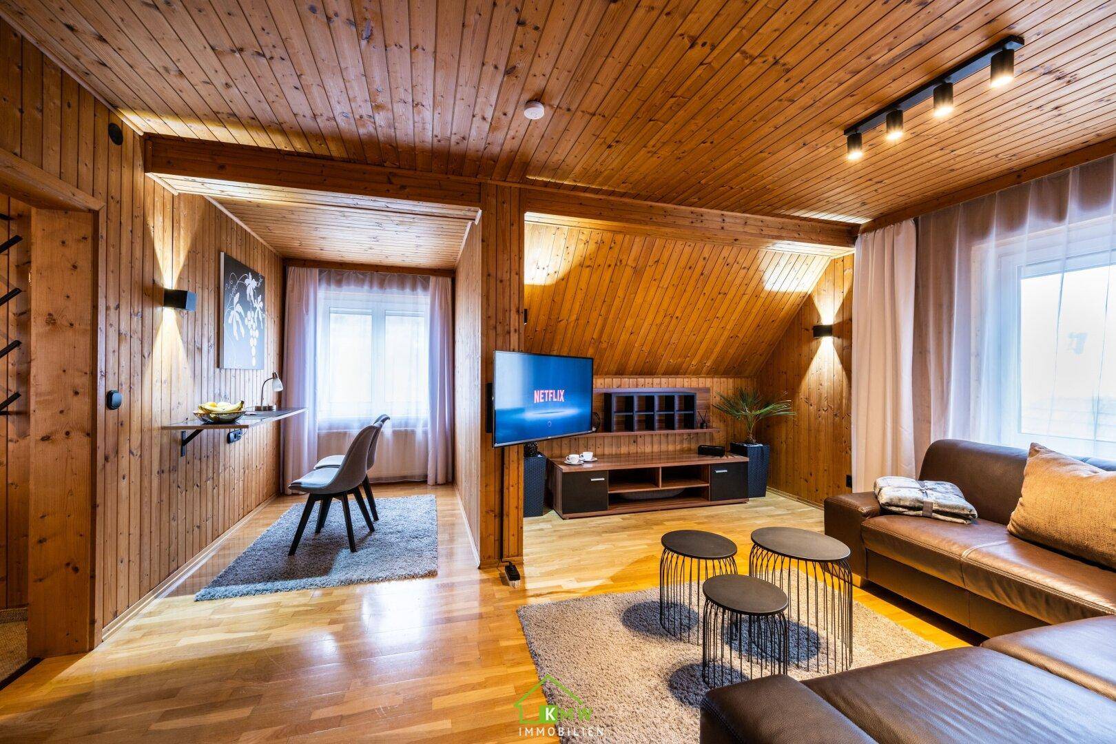 Gemütlicher Wohnbereich mit Holzvertäfelung, bequemer Couch und Blick auf die Umgebung.