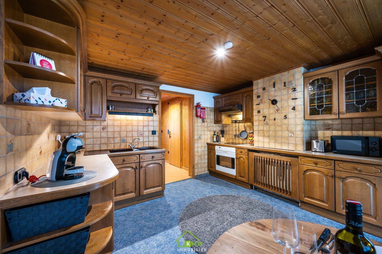 Gemütliche Holzküche mit integrierten Geräten, Fliesen und Teppichboden.