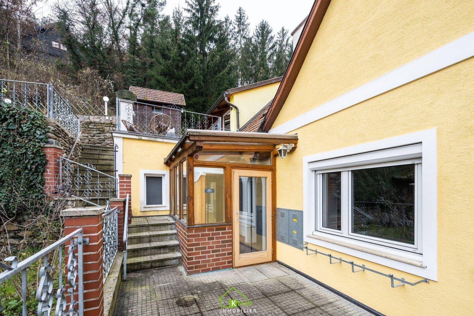Eingangsbereich des Hauses mit verglastem Vorbau und Zugang zur Terrasse.