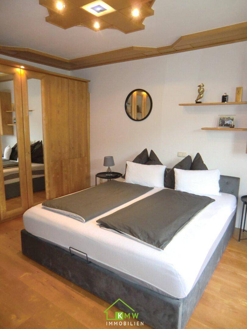 Gemütliches Schlafzimmer mit Holzboden, Einbauschränken und indirekter Deckenbeleuchtung.