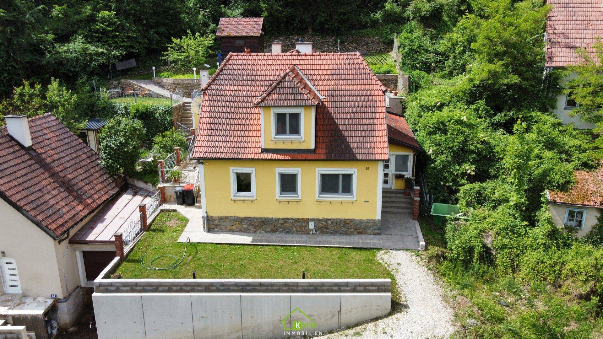 Vogelperspektive des gelben Hauses mit rotem Ziegeldach und gepflegtem Vorgarten.