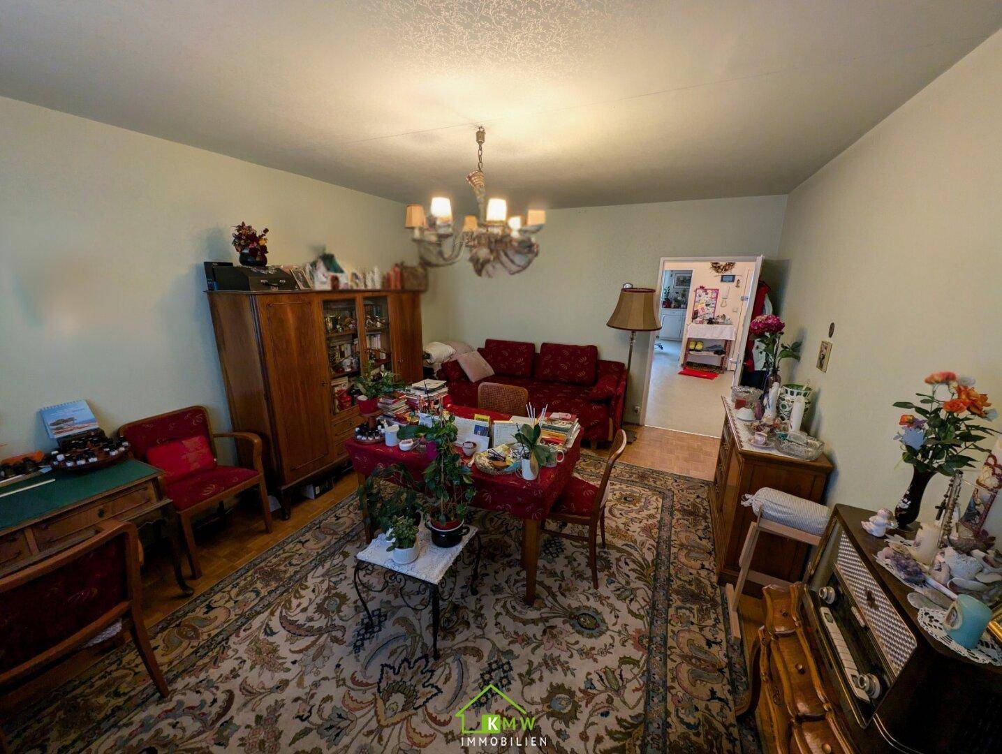 Gemütliches Wohnzimmer mit traditionellen Holzmöbeln, gemustertem Teppichboden und elegantem Kronleuchter.