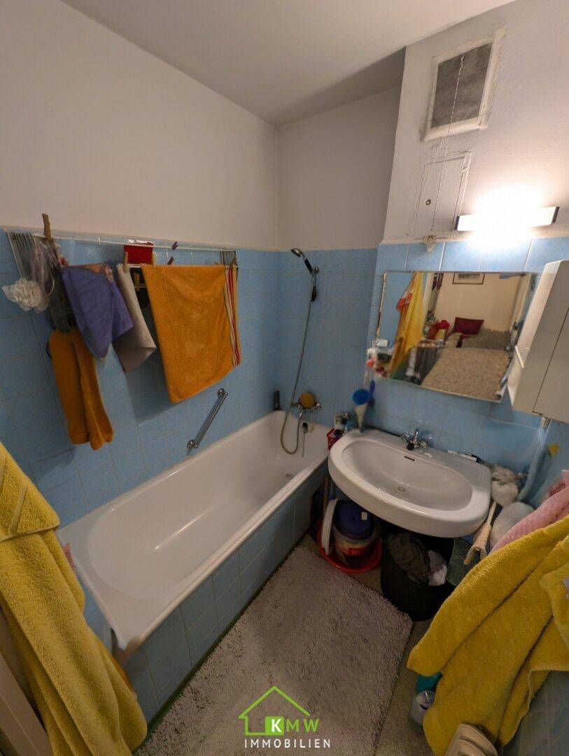 Badezimmer im Stil der 80er Jahre mit blauen Fliesen, Badewanne und Waschbecken.